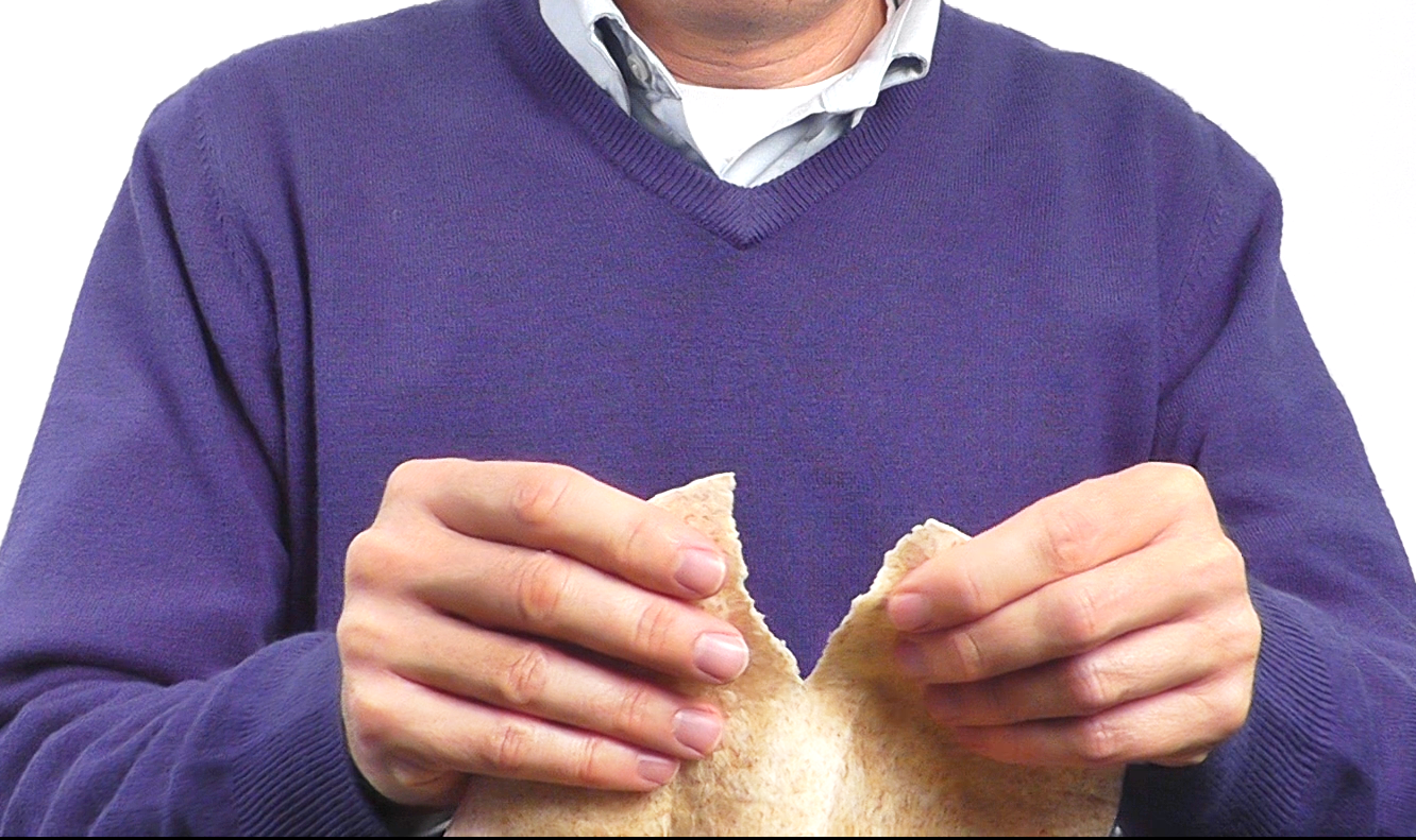 Person tearing a flour tortilla bread as a sensory interaction relating to freshness